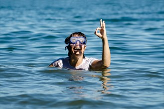 Woman with Diving Mask in the Water and Showing the OK Signal