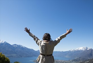 Woman with Arms Outstretched with Mountain and Lake View over Locarno in a Sunny Day in Ticino in Switzerland