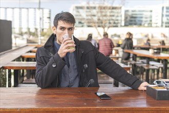 Businessman sitting at an outdoor bar drinking lemonade