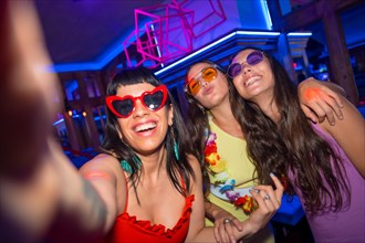 Friends in a nightclub taking a selfie at a night party in a pub