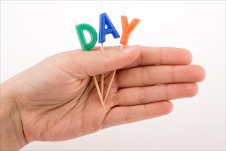 Color candles on sticks in hand write the word day