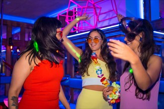 Female friends in a disco dancing smiling at a night party on summer vacation in a pub