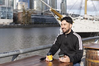 Latin tourist drinking coffee at an outdoor bar in Puerto Madero