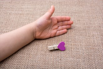 Clothespin with a heart shaped object in hand on canvas