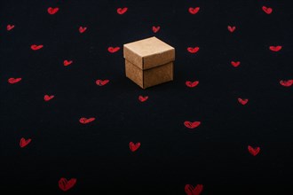 Brown cardboard box on black background with red hearts