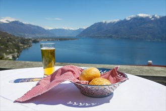 Table with Bread and a Glass of Beer With Panoramic View over Alpine Lake Maggiore with Snowcapped Mountain in a Sunny Day in Ticino