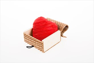 Red heart shaped object placed in a straw box on white background