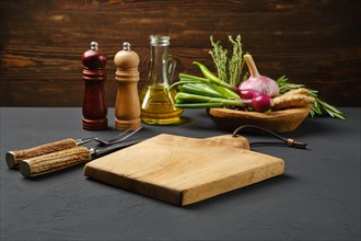 Empty wooden cutting board surrounded with spice and seasonings