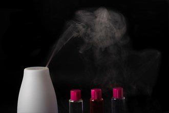 Aroma humidifier steaming with scent pots isolated on a black background