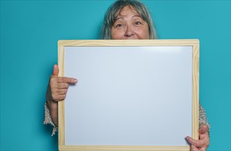 Older white-haired woman holding a white board to paste text on