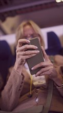 Close-up of a mature woman's hands using a smartphone while traveling by train