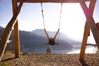 Woman on a Swing with Mountain View and Sunlight over Lake Lugano in Morcote