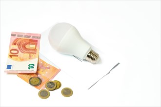 Light bulb on an electricity bill and banknotes and coins on a white background.concept of electricity price increase