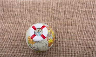 Life preserver on top of globe on canvas background