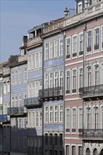 Row of houses with pastel-coloured facades and iron balconies