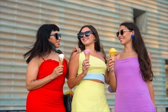 Portrait of young female friends eating ice cream on summer vacation by the beach