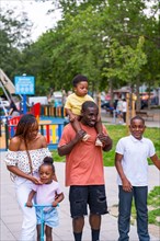Portrait of African black ethnic family with children in playground of city park
