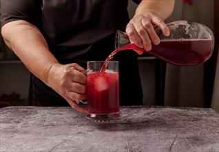 Waitress dressed in black serving a pitcher of sparkling summer red wine on ice from a glass decanter