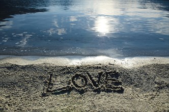 Love Written in the Sand Beach close to the Water with Sunlight