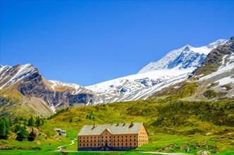 Big Building with Snow-capped Mountain and Blue Sky in Simplon Pass in Summer in Valais