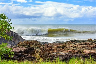 Wave breaking behind the rocks in Serra Grande on the rocky coast of Bahia