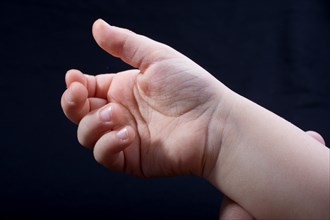 Five fingers of a child hand partly seen in black background