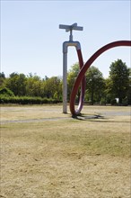 Withered meadow and sculpture of a water tap