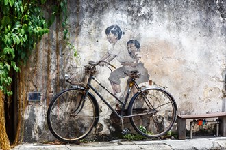 Street art boy and girl on bicycle on a wall in George Town on Penang Island