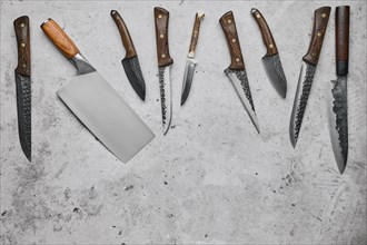 Various types of knives scattered on concrete background