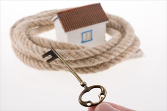 Key and house surrounded by rope on a white background