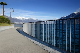Walkway with Railing on Alpine Lake Maggiore with Snow-capped Mountain in Ticino