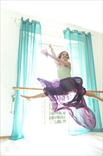 Woman Jumping and Doing the Splits Against a Window with Curtain with Transparent Skirt