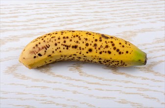 Single yellow freckled bananas on a wooden texture