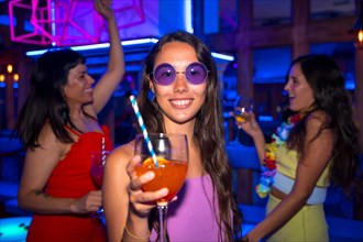 Portrait attractive woman toasting and having fun with a glass of alcohol in a nightclub at a night party