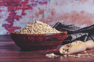 Oatmeal in a wooden bowl on a wooden table with a brick wall in the background