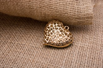 Heart shaped gold color metal object on canvas