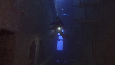Scuba diver with lantern floats inside of ferry Salem Express shipwreck