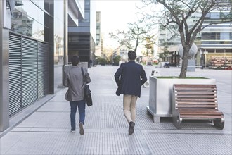 Back view of two latin businessmen walking down the street