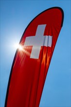 Swiss Banner Flag with Sunlight and Against Blue Sky in Switzerland