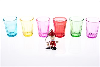 Colorful drinking glass lined up with a doll at the front on white background