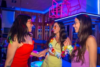 Female friends in a nightclub having fun at a night party on summer vacation in a pub