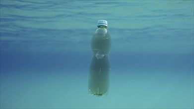 Green plastic bottle drifting under surface of blue water. Plastic pollution of Ocean