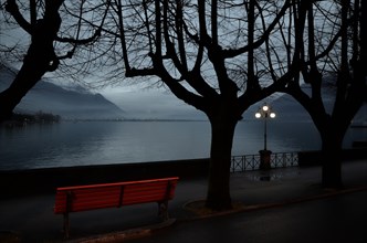 Red Bench and Illuminated Street Lamp on the Waterfront at night in Locarno
