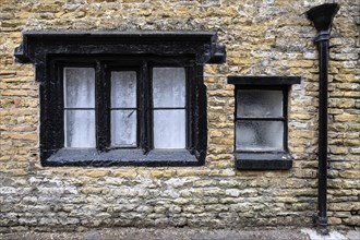 Old window frames and rainwater drainpipe on an old stone house in the old town of Bourton on the Water