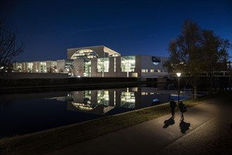 Two people stand out in front of the Federal Chancellery at blue hour