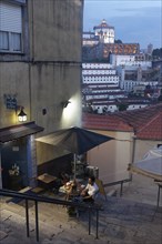 Two restaurant guests sitting at a table in a steep staircase with a view of the Serra do Pilar monastery
