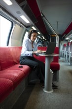 Business Woman Sitting on a Sofa and Working on Laptop in First Class in a Train in Switzerland