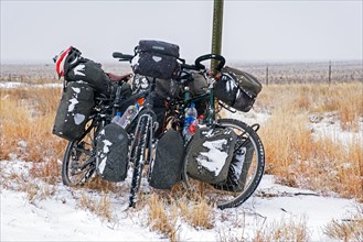 Two heavily laden trekking bicycles with big panniers in the snow in winter