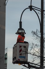 Man in high-visibility waistcoat repairs street lamp