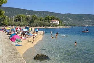 Sunbathers on sandy beach and tourists swimming in the Adriatic Sea near Cres on the island Cherso